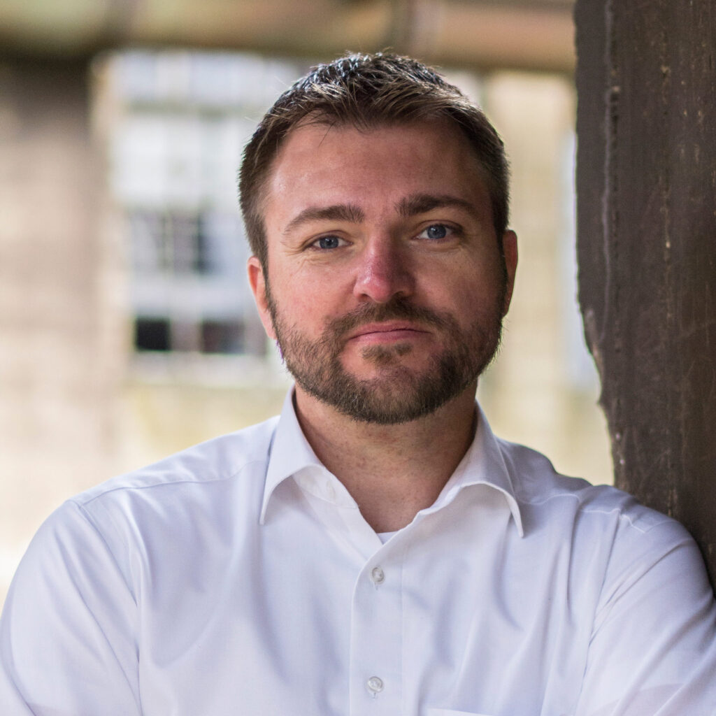 Das Bild zeigt einen Mann in einem weißen Hemd, mit kurzen Mittelblonden Haaren und einem kurzen Vollbart. Es ist Prof. Dr. Marc Jansen